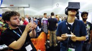 Software designer Julian Kantor who created "The Recital" takes a picture of Jonathan Feng as he uses the Oculus Rift virtual reality headset to experience his program during E3 in Los Angeles