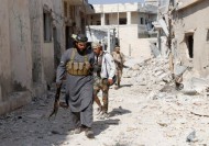 Rebel fighters carry their weapons as they walk towards their positions in the town of Morek in Hama province
