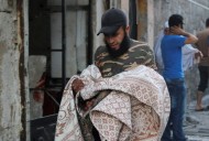 A man carries a body covered with a blanket at a site hit by what activists said was an airstrike by forces loyal to Syria's President Bashar al-Assad in Qadi Askar district in Aleppo