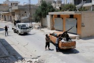Rebel fighters man anti-aircraft weapons mounted on pick-up trucks as they look at the sky in the town of Morek in Hama province
