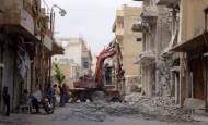 Residents work on removing debris from what activists say was caused by shelling by forces loyal to Syria's President Bashar Al-Assad in central Raqqa