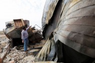 A man points at damage at an oil refinery and a gas station that were targeted by what activists said were U.S.-led air strikes, in Tel Abyad