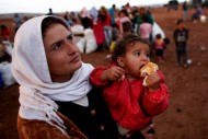 Syrian Kurdish refugees wait for transportation after crossing into Turkey from the Syrian border town Kobani, near Suruc