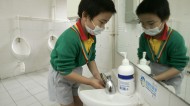 A kindergarten student wears a mask as he washes his hands in Hong Kong