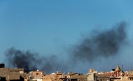 Black smoke billows in the sky above areas where clashes are taking place between pro-government forces, who are backed by the locals, and the Shura Council of Libyan Revolutionaries, an alliance of former anti-Gaddafi rebels