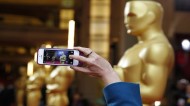 A person uses a phone to take a picture of an Oscars statue at the 86th Academy Awards in Hollywood