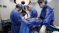 Surgeons remove damaged tissue and liquid silicone from a patient, in Caracas