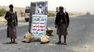 Followers of Yemen's al-Houthi Shi'ite group stand next to the image Huthi in Saada