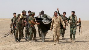 Iraq's Shi'ite paramilitaries and members of Iraqi security forces hold an Islamist State flag which they pulled down in Nibai, in Anbar province