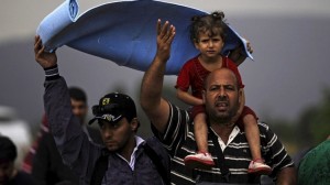 A man carrying a child on his shoulders reacts at Greece's border with Macedonia, while waiting to enter Gevgelija, Macedonia