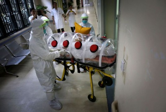 Medical personnel take pictures with mobile phones as health workers in protection suits transport mock patient into quarantine ward during drill to demonstrate procedures of handling Ebola victims, at a hospital in Guangzhou