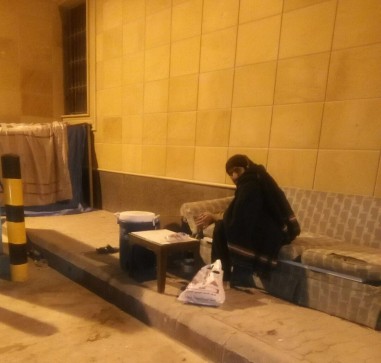 العامل يجلس على الطريق في البرد حارسا لمعدرات الشركة