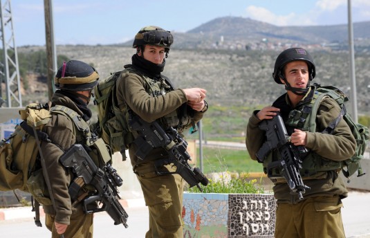 Israeli soldiers guard the road to the Israeli settlement Itamar where five family members were killed by a Palestinian late Friday night